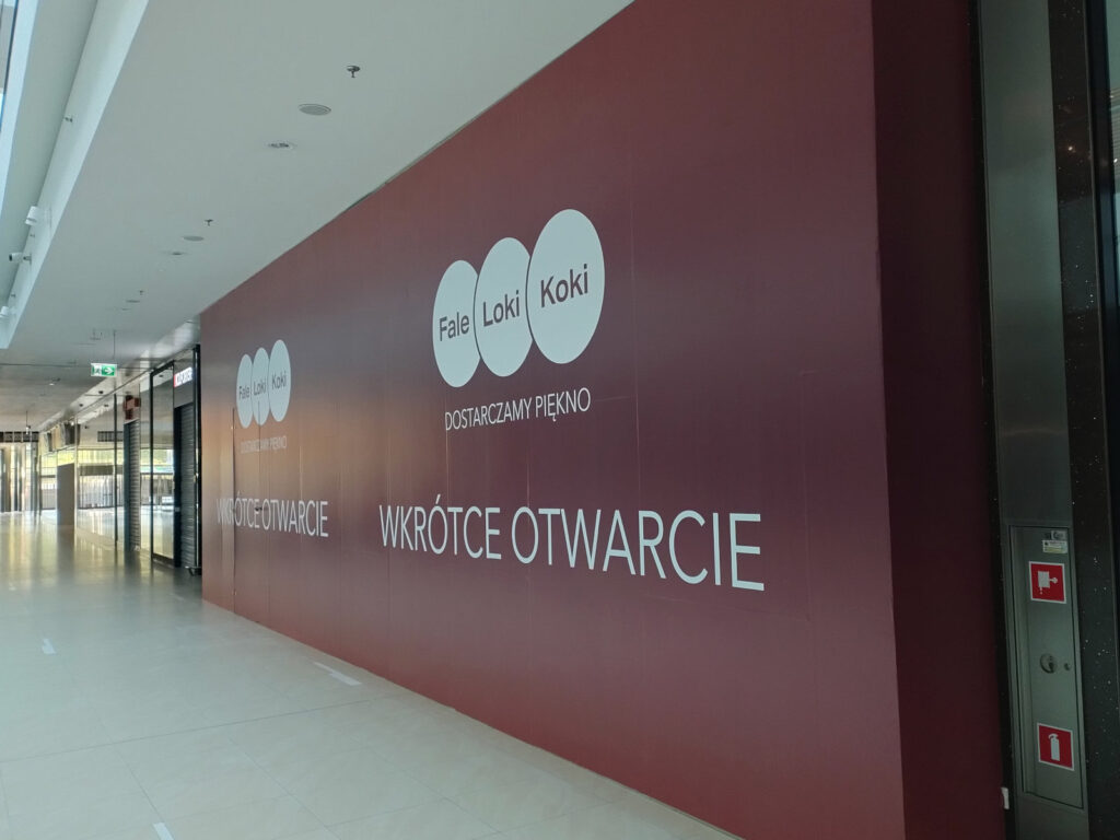 montaż folii reklamowej na ścianie tymczasowej salonu z produktami beauty